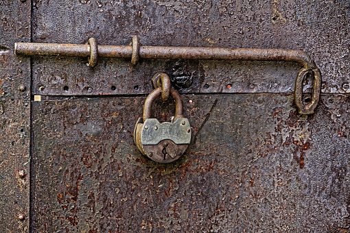 Landscape photo of a latch attached to the wall with copy space available to the right of the hanging latch
