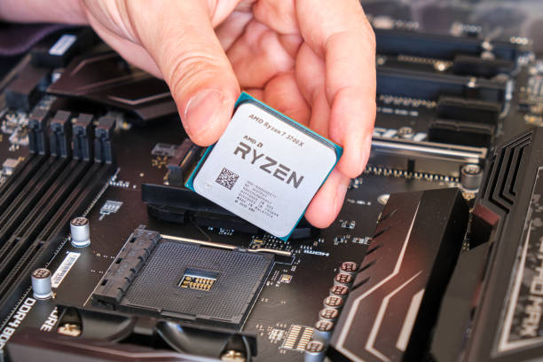AMD Ryzen 3700X CPU in technician fingers, above a motherboard, part of a custom PC build. stock photo