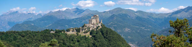 Sacra di San Michele or Saint Michael's Abbey and the alps, Piedmont, Italy. Panoramic view during summer. stock photo