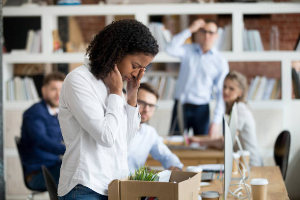 Sad african female employee packing belongings in box got fired Sad african female young employee packing belongings in box at workplace got fired from job, stressed upset black worker intern leaving office on last day at work crying after unfair dismissal being fired photos stock pictures, royalty-free photos & images