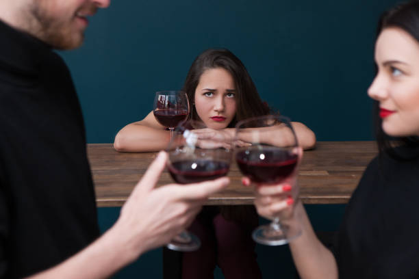 Sad alone female in bar. Jealousy backdrop Sad alone female in bar. Jealousy backdrop. Love triangle, cheating relationships. Unhappy betrayed woman in focus on blue background, loneliness concept envy stock pictures, royalty-free photos & images