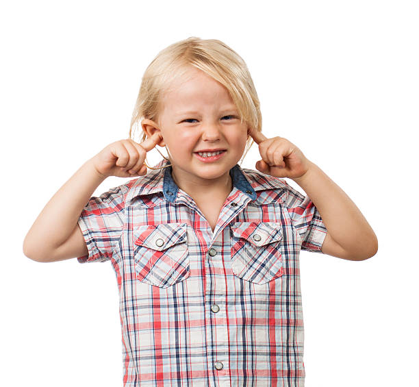 Sad boy blocking his ears A cute sad boy looking distressed and blocking his ears with his fingers. Isolated on white. Fingers in Ears stock pictures, royalty-free photos & images