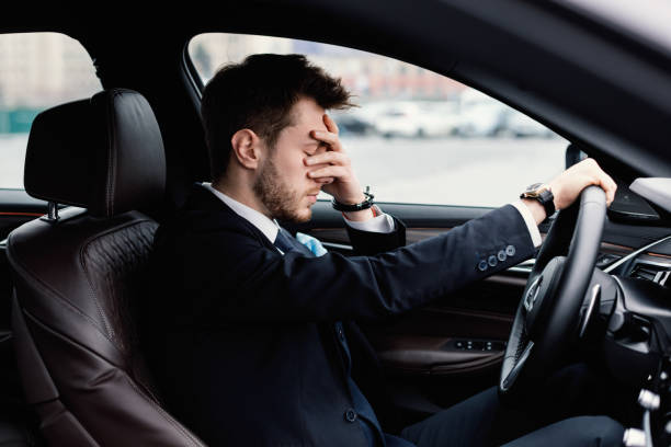Sad businessman driving alone in his new car Feeling Anxiety. Exhausted, overloaded man closing eyes with hand, experiencing headache or stress man driving suit stock pictures, royalty-free photos & images