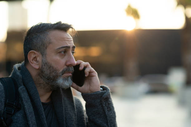 Sad businessman talking on the phone at street after work stock photo