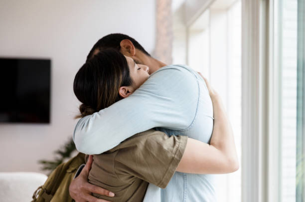 Sad female soldier leaves home Sad mid adult  female soldier hugs her husband goodbye as she leaves for military duty. embracing stock pictures, royalty-free photos & images