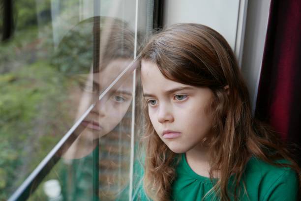 Sad girl looking out the window stock photo