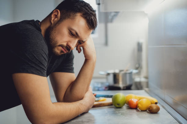 Sad man leaning on the kitchen countertop stock photo