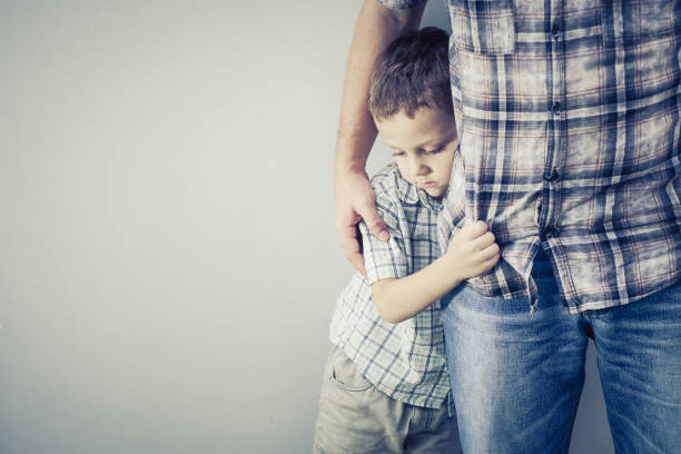 sad son hugging his dad sad son hugging his dad near wall at the day timesad son hugging his dad near wall at the day time shy photos stock pictures, royalty-free photos & images