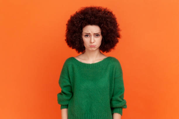 Sad unhappy woman with Afro hairstyle wearing green casual style sweater looking at camera with pout lips, being upset of bad news. stock photo