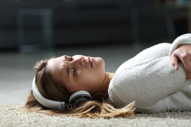 wanita sedih mendengarkan musik di lantai - sad sing potret stok, foto, & gambar bebas royalti