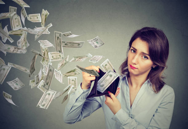treurige vrouw toont haar portemonnee met geld dollar biljetten vliegen weg - geldstress stockfoto's en -beelden