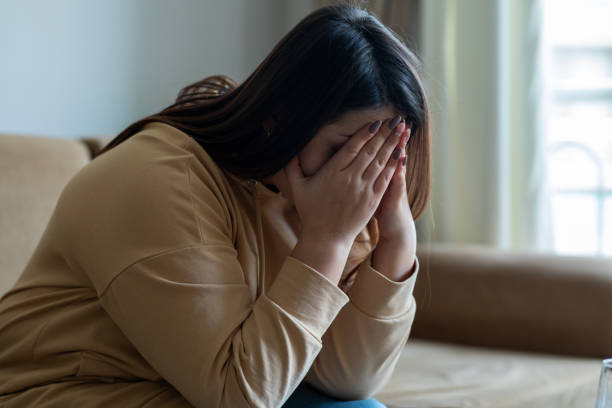 Sad woman sitting on a sofa in the living room Sad woman sitting on a sofa in the living room heartbreak stock pictures, royalty-free photos & images