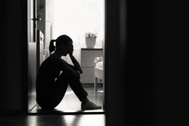 Sad young woman sitting on a floor at home stock photo