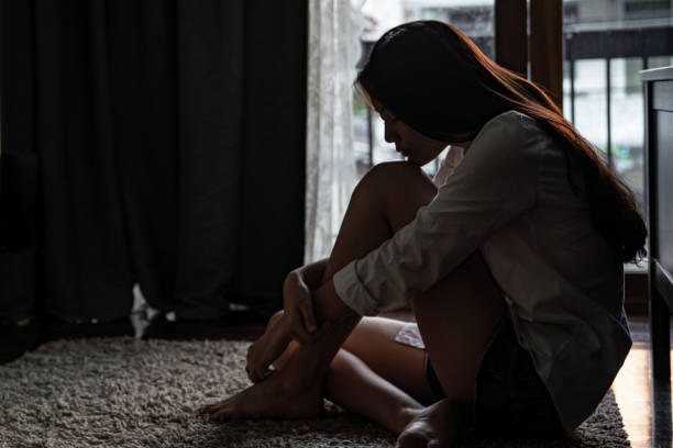 Sadness teenage girl sitting alone on the floor Selective focus loneliness young asian woman sitting on bedroom floor near the balcony. Depression sadness breaking up asian teenage girl sitting alone hugging knees closing eyes and thinking. sadness stock pictures, royalty-free photos & images