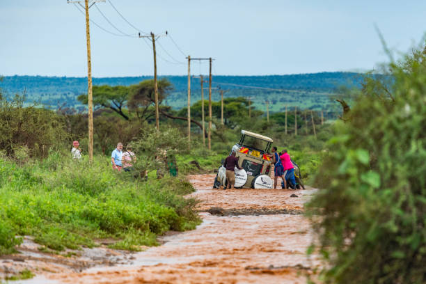 Safari vehicle bogged on flooded dirt road, Amboseli National Park, Kenya. stock photo