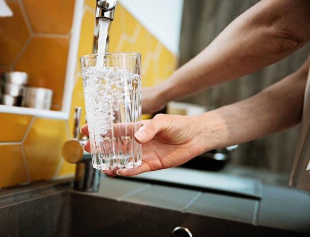 Safe Drinking Tap Water woman filling a glass with filtered water right from the tap filtration stock pictures, royalty-free photos & images