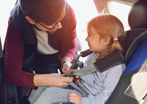 Safety first, father puts child in car seat stock photo