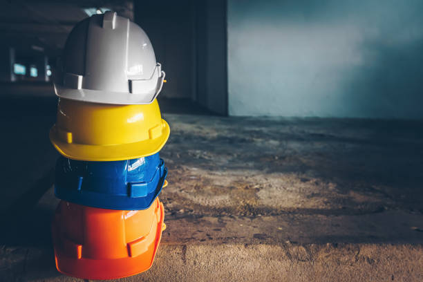 Safety helmet, white, yellow, blue and orange, placed on the cement floor in the construction site. Safety helmet, white, yellow, blue and orange, placed on the cement floor in the construction site. hardhat stock pictures, royalty-free photos & images