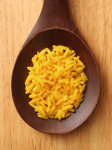 Top view of wooden spoon with saffron rice on it