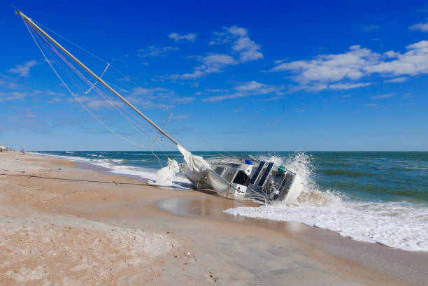 Sailboat capsized on a Florida beach Sailboat washed up on shore after Hurricane Irma on Vilano Beach, Florida (USA) capsizing stock pictures, royalty-free photos & images