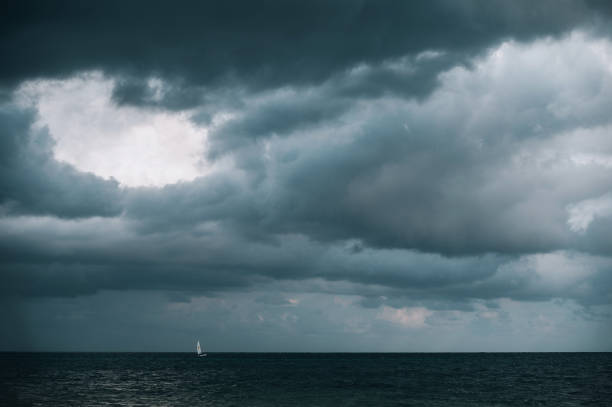 Sailboat in the distance under the storm clouds stock photo