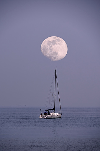 Sailboat sailing in the sea with the moon, full moon, dusk, cold tomes, aligned
