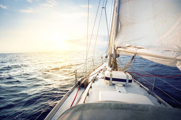 Sailing at sunset, a view from the yacht’s deck to the bow and sails stock photo