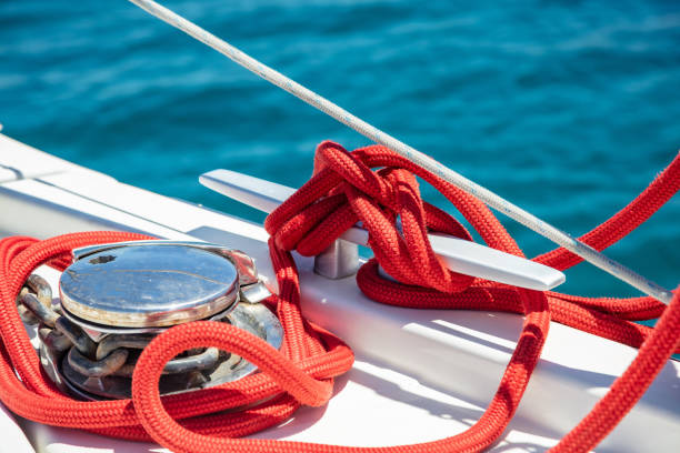 Sailing boat mooring rope tied on cleat. Heavy metal chain around the winch stock photo