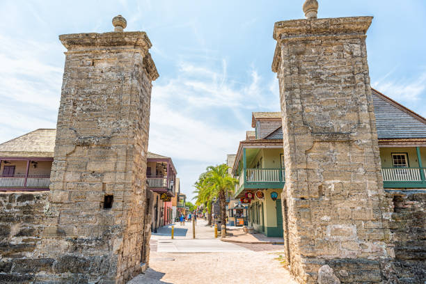 Saint George Street and people walking on sunny day by stores in downtown old town Florida city with stone gate entrance stock photo