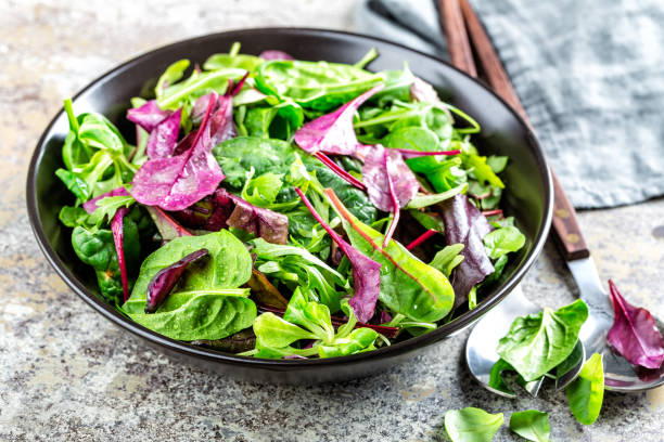 Salad bowl, healthy food. Fresh salad mix of baby spinach, arugula leaves, basil, chard and lambs lettuce. stock photo
