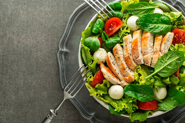 Salad with chicken breast and mozzarella Healthy green salad with chicken breast and mozzarella on grey background chicken salad stock pictures, royalty-free photos & images