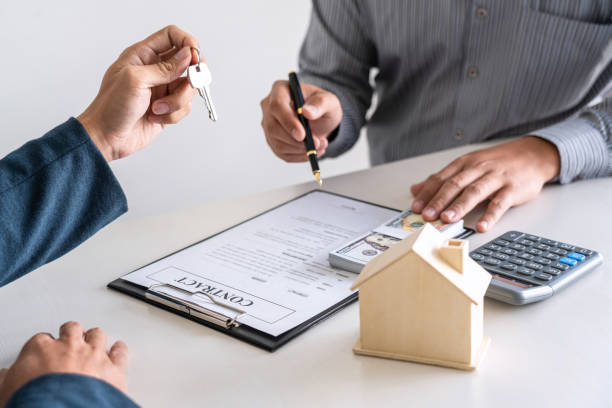 Sale purchase contract to buy a house, Real estate agent are presenting home loan and giving keys to customer after signing contract to buy house with approved property application form stock photo
