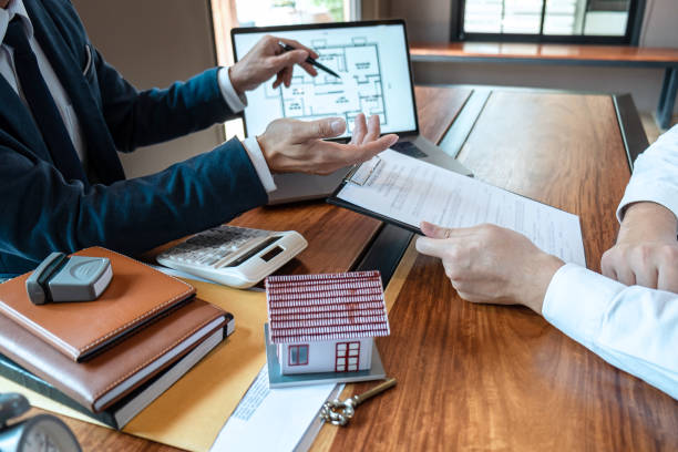 Sale purchase contract to buy a house, Real estate agent are presenting home loan and giving keys to customer after signing contract to buy house with approved property application form stock photo