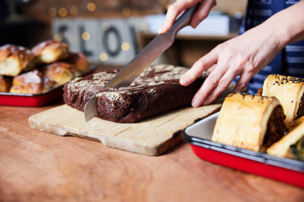Sales Assistant In Bakery Cutting Freshly Baked Baked Brownies On Counter stock photo