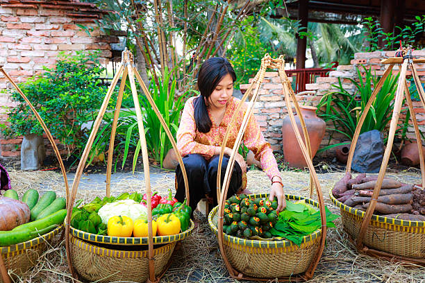 salesgirl with her bamboo basket full of vegetables Hochiminh City, Vietnam - March 5, 2016 : salesgirl with her bamboo basket full of vegetables in the culinary fair at the Van Thanh tourist area, Ho Chi Minh City which is modeled on the traditional market in the village Vietnam salesgirl stock pictures, royalty-free photos & images