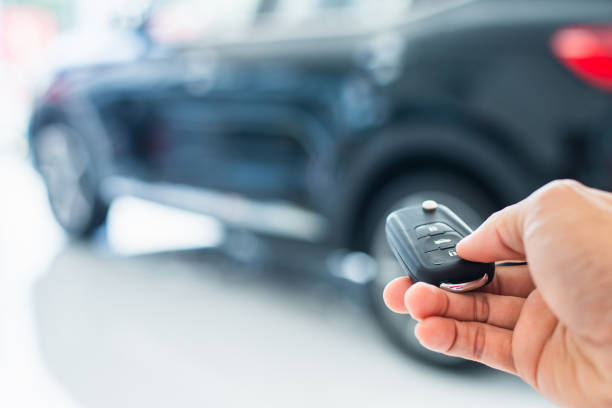 Salesman is carrying the car keys delivered to the customer at the showroom with a low interest offer. Special promotion, auto business, car sale, deal, gesture and people concept. stock photo