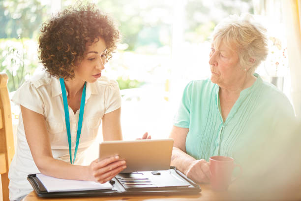 salesperson with senior a care worker or medical professional or housing officer makes a house call to a senior client at her home . She is discussing the senior woman’s options on her digital tablet. assisted living consultant stock pictures, royalty-free photos & images