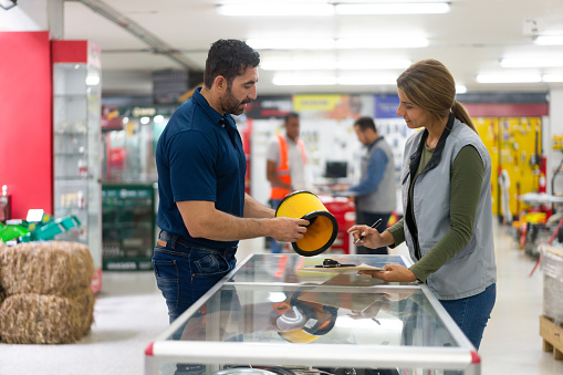 Latin American saleswoman helping a customer buying tools at a hardware store - small business concepts
