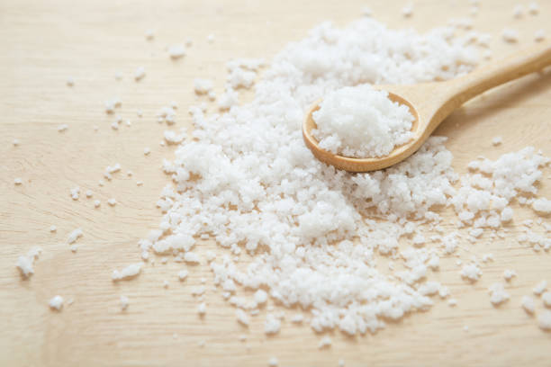 Salt in wooden spoon on the kitchen table and copy space stock photo