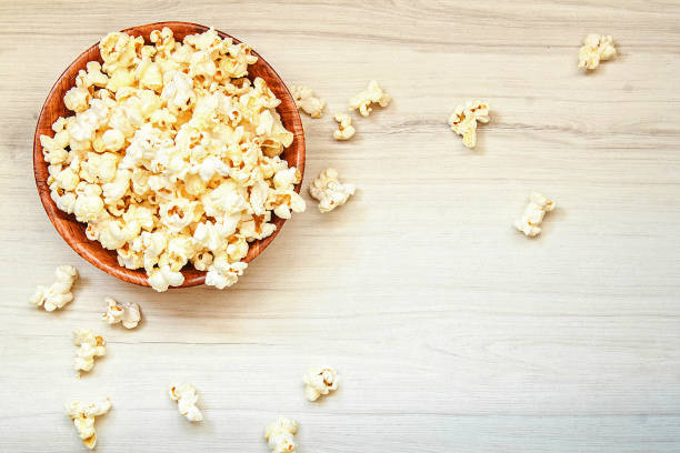 Salt popcorn in the wooden bowl on the wooden table. stock photo