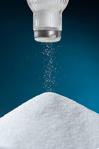 salt shaker with salt coming out onto big pile - zout stockfoto's en -beelden