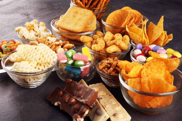 Salty snacks. Pretzels, chips, crackers in glass bowls on table stock photo