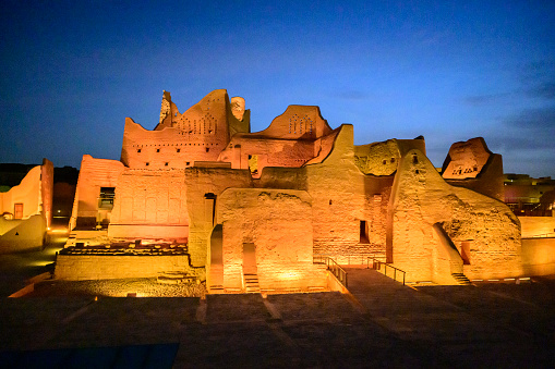 Wide angle view of At-Turaif open air museum and UNESCO World Heritage Site near Riyadh, mud-brick architecture illuminated under blue hour sky. Property release attached.