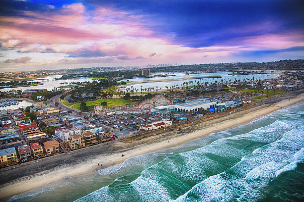 San Diego's Mission Beach Aerial View The iconic "Big Dipper" roller coaster at Belmont Park featured in the center of this aerial photograph of Mission Beach in San Diego, California.  The downtown skyline is visible in the distance.  I shot this image nearing dusk after a storm had cleared from an altitude of about 300 feet during a helicopter photo flight.   mission beach san diego stock pictures, royalty-free photos & images