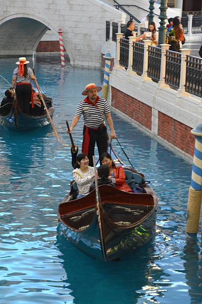 San Luca Canal, The Venetian Casino, Macau Macau, Macau - March 24, 2014: an indoor replica of San Luca Canal with Gondolas and singing gondoliers at the Venetian Macao, the largest casino in the world, and the largest single structure hotel building in Asia. In the background tourists walking along the artificial canal. the venetian macao stock pictures, royalty-free photos & images