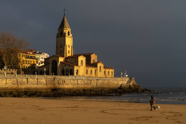 스페인 아스투리아스 주 지존시의 일출에 햇살이 비추는 산 로렌조 해변의 산 페드로 교회 - luis lorenzo 뉴스 사진 이미지