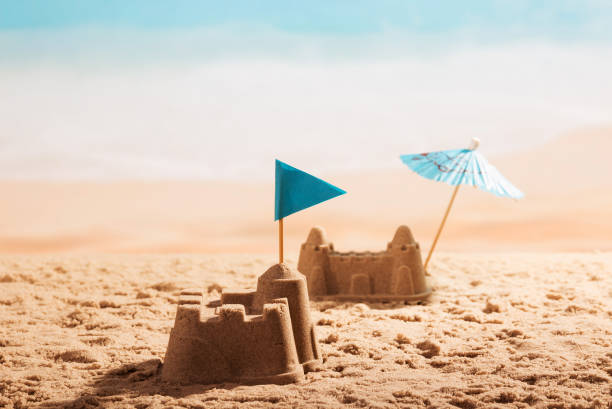 Sandcastles with flag and umbrella on the beach. stock photo