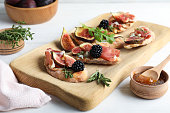Sandwiches with ripe figs and prosciutto served on white wooden table
