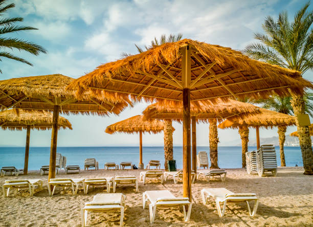 Sandy and sunny beach of the Red Sea with sunshades, chairs and deck-chairs in Eilat stock photo