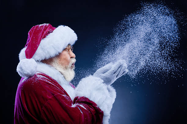 Santa Claus blowing a handful of snow stock photo